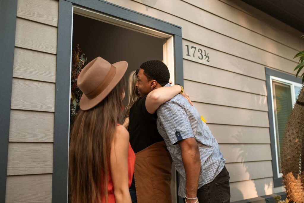 a person hugging a man at the doorway, hopefully before going on a wineries tour