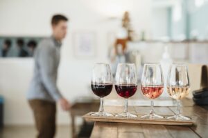 A group of wine glasses on a table at a winery with a man in the background.