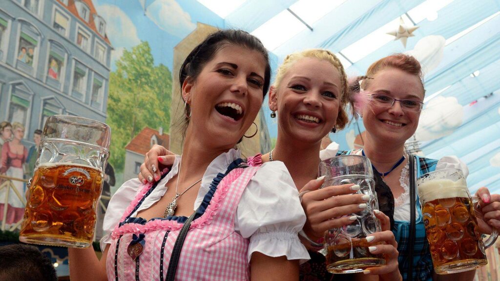 Three girls in outfits, holding beers