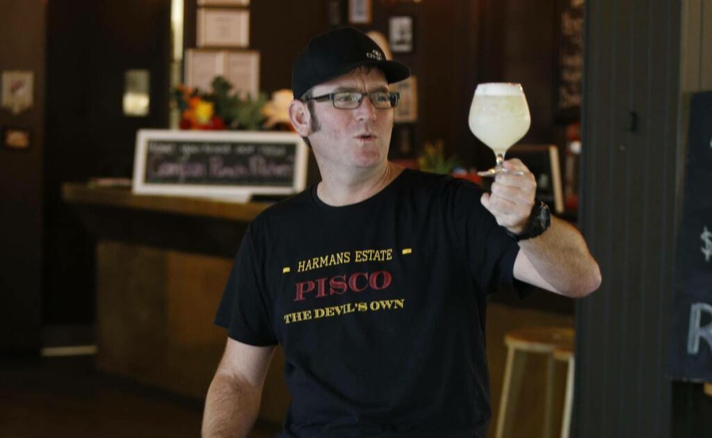Man in black tshirt holds a glass of pisco in South Australia